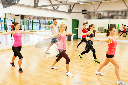 Image of group of smiling people exercising in the gym