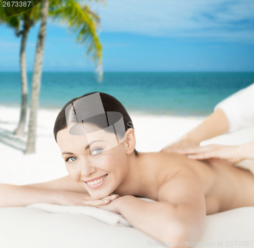 Image of smiling woman in spa salon getting massage