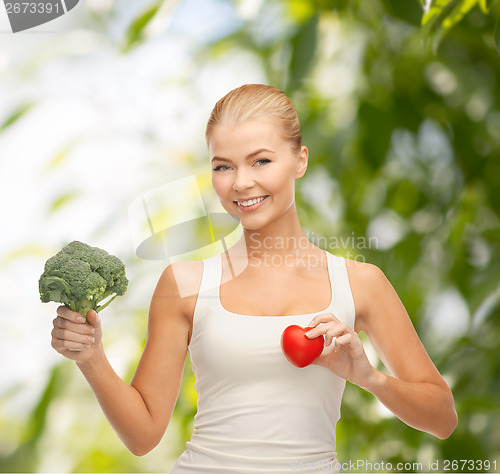 Image of smiling woman holding heart symbol and broccoli