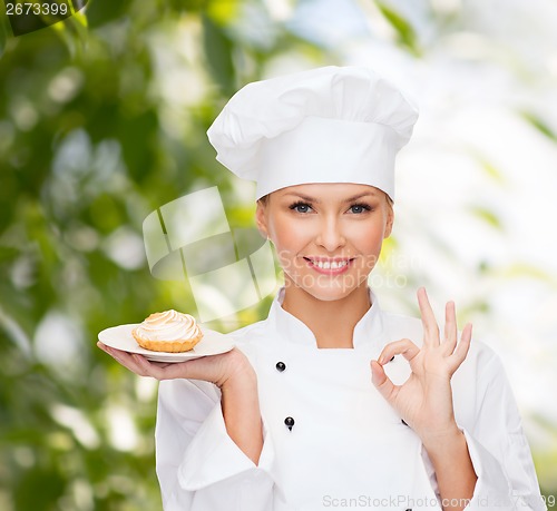 Image of smiling female chef with cake on plate