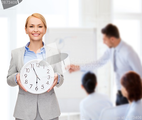 Image of smiling businesswoman with wall clock