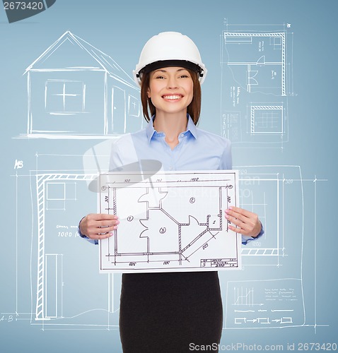 Image of smiling businesswoman in helmet showing blueprint