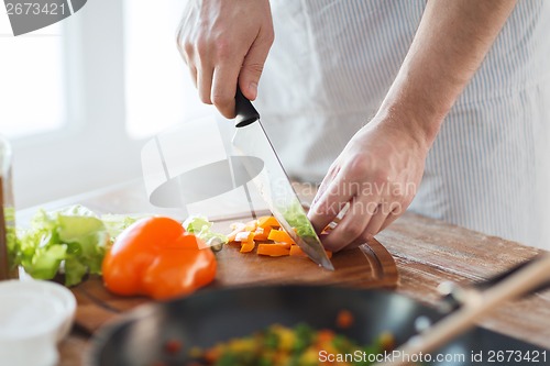 Image of close up of male hand cutting pepper on board