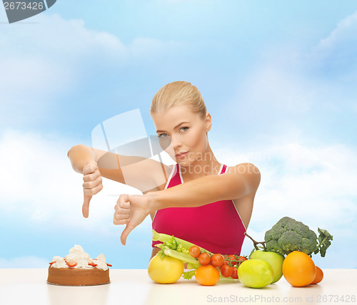 Image of woman with fruits showing thumbs down to cake