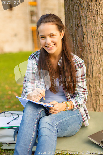 Image of smiling teenager writing in notebook