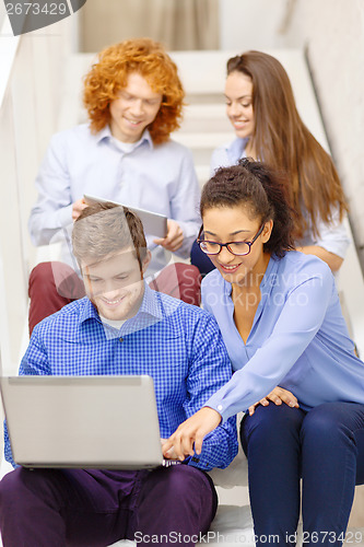 Image of team with laptop and tablet pc on staircase