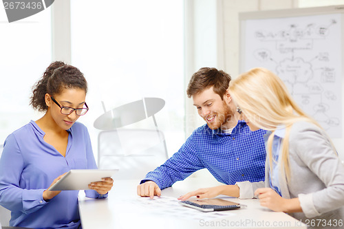 Image of smiling team with table pc and papers working