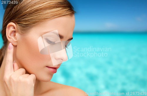 Image of calm woman touching her ear