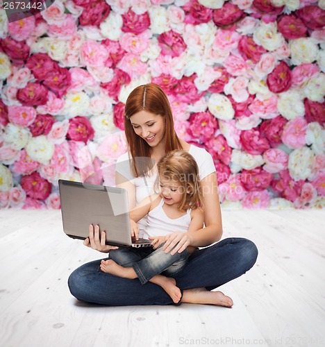 Image of happy mother with adorable little girl and laptop
