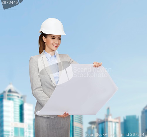 Image of smiling architect in white helmet with blueprints