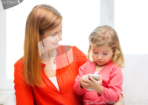 Image of happy mother and daughter with smartphone at home