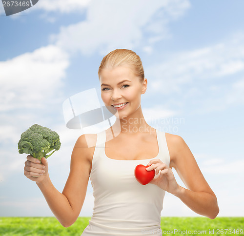 Image of smiling woman holding heart symbol and broccoli