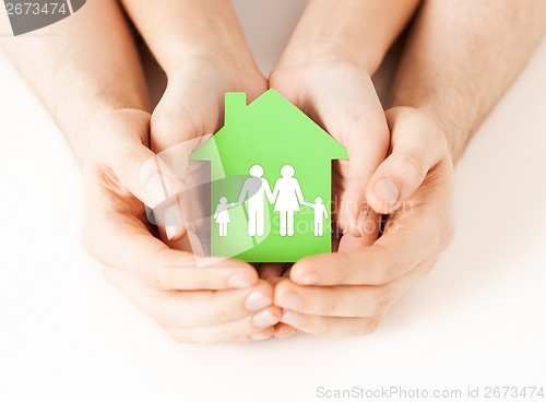 Image of hands holding green house with family