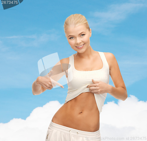 Image of beautiful sporty woman pointing at her abs