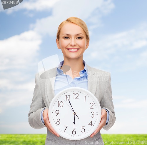 Image of smiling businesswoman with wall clock