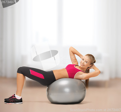 Image of smiling woman with fitness ball at home