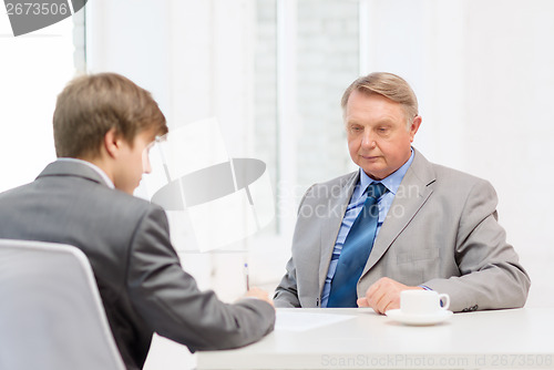 Image of older man and young man signing papers in office