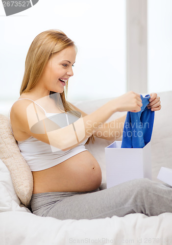 Image of smiling pregnant woman opening gift box