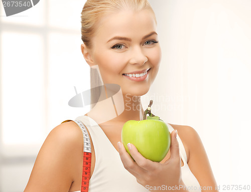 Image of sporty woman with apple and measuring tape