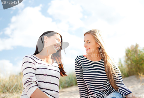 Image of smiling girlfriends having fun on the beach