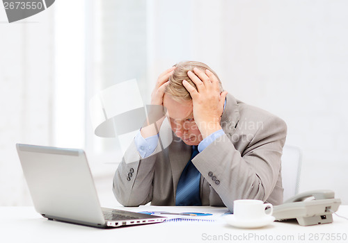 Image of upset older businessman with laptop and telephone