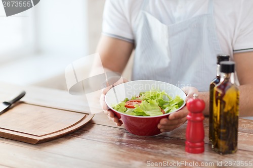 Image of close of male hand holding a bowl with salad