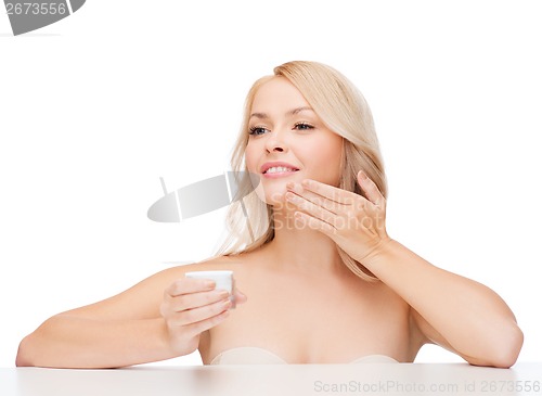 Image of beautiful woman applying cream on her skin