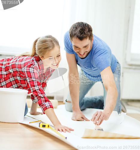 Image of smiling couple smearing wallpaper with glue