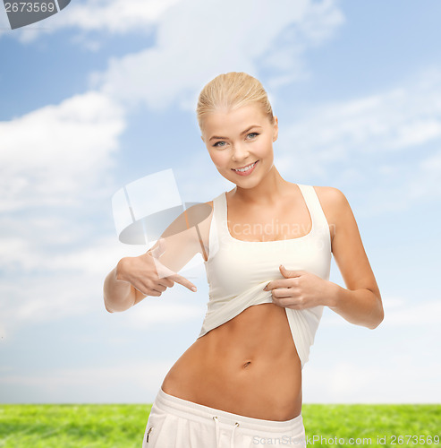 Image of beautiful sporty woman pointing at her abs