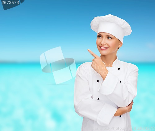 Image of smiling female chef pointing finger to sonething