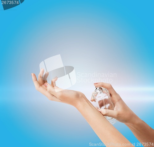 Image of woman hands spraying perfume