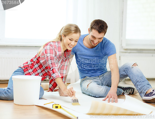 Image of smiling couple smearing wallpaper with glue