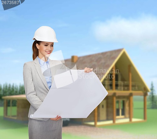 Image of smiling architect in white helmet with blueprints