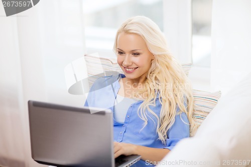 Image of smiling woman with laptop computer at home