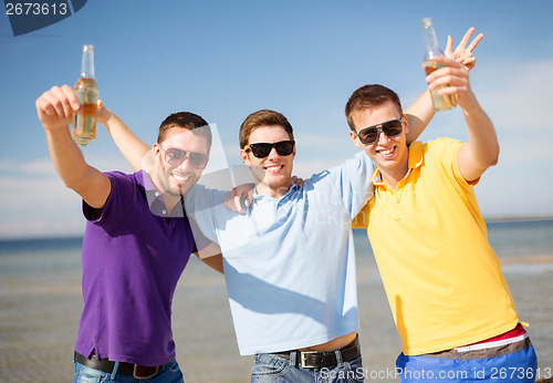 Image of male friends on the beach with bottles of drink