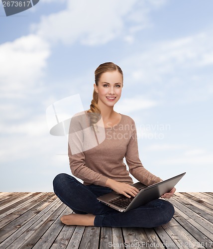 Image of young woman sitting on floor with laptop