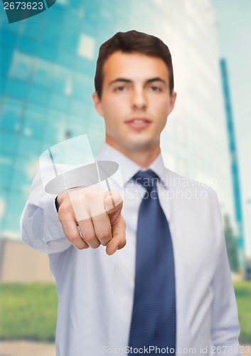 Image of friendly young buisnessman pointing finger