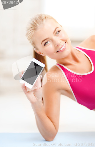 Image of smiling woman lying on the floor with smartphone