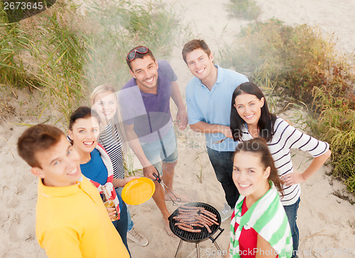 Image of group of friends making barbecue on the beach