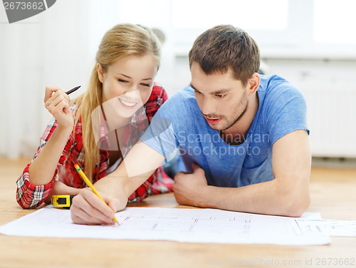 Image of smiling couple looking at blueprint at home