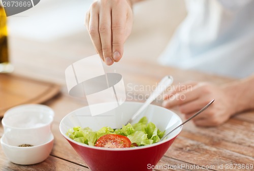 Image of close up of male hands flavouring salad in a bowl