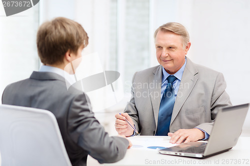 Image of older man and young man having meeting in office