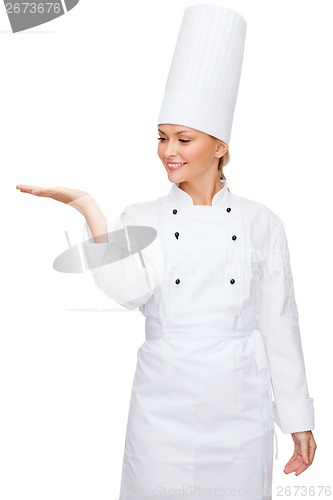 Image of smiling female chef holding something on hand