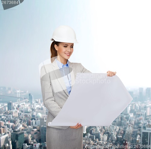 Image of smiling architect in white helmet with blueprints