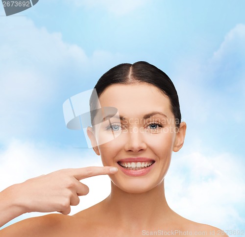 Image of young calm woman pointing to her mouth