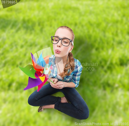 Image of woman in eyeglasses sitting on floor with windmill