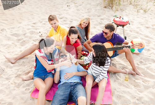 Image of group of friends with guitar having fun on beach