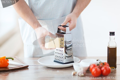 Image of close up of male hands grating cheese