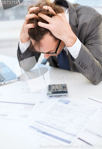 Image of businessman with papres, laptop and calculator