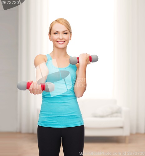 Image of young sporty woman with light dumbbells